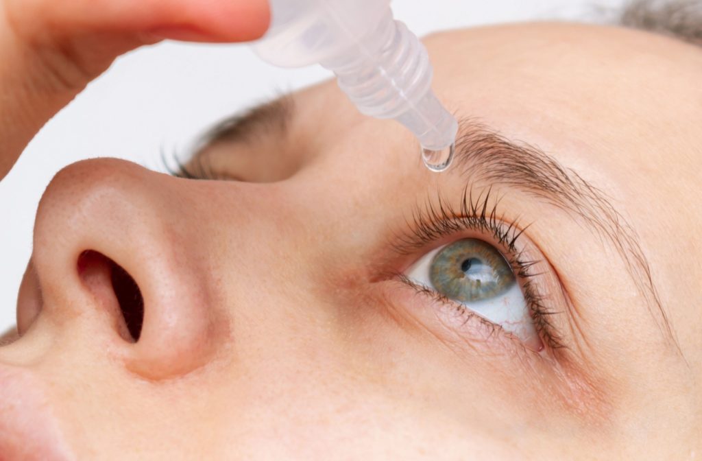 A close-up image of a person dropping eye drops into their dry eyes for relief.