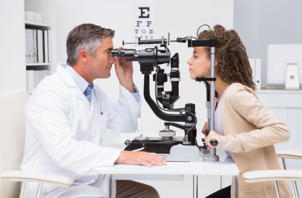 An optometrist examining a patient's eyes during an eye exam to find out if IPL or RF could treat their dry eyes.