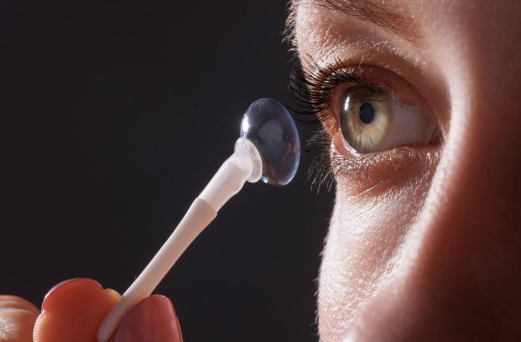 Close-up of a person’s eye as they prepare to insert an ortho-k contact lens using an applicator tool, showing detailed focus on the lens and eyelashes.